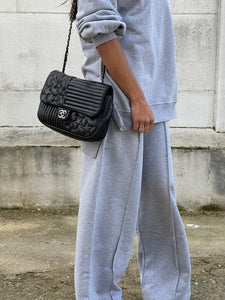 Style urbain décontracté avec tenue en gris chiné et sac à main noir matelassé.
